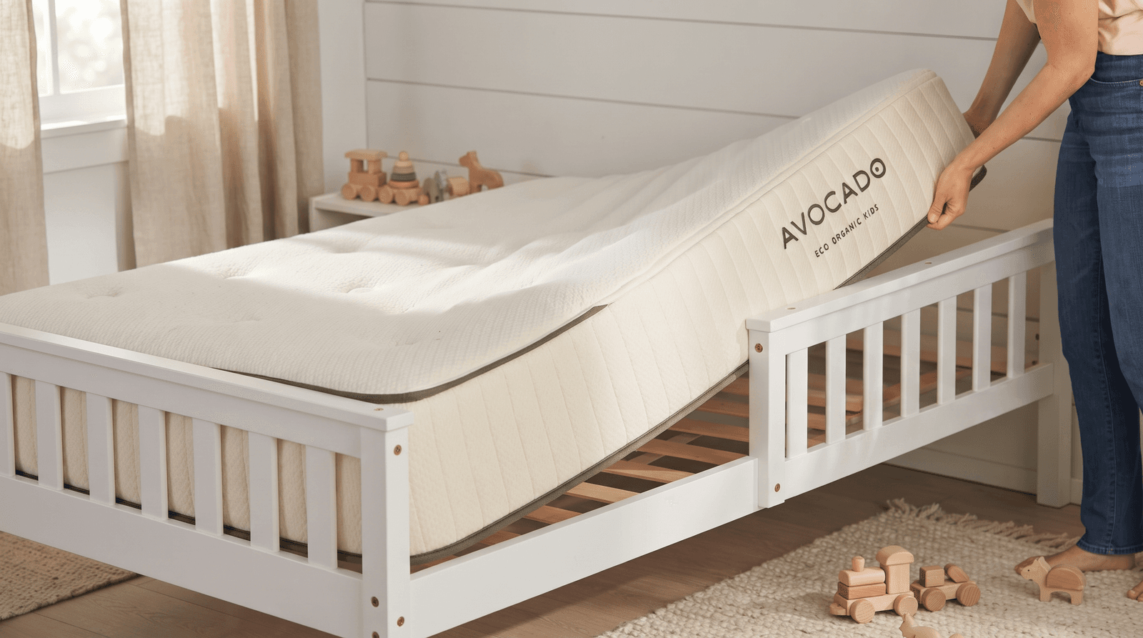 Avocado Eco Organic Kids Mattress with an ivory quilted cover on a white kids' bed frame