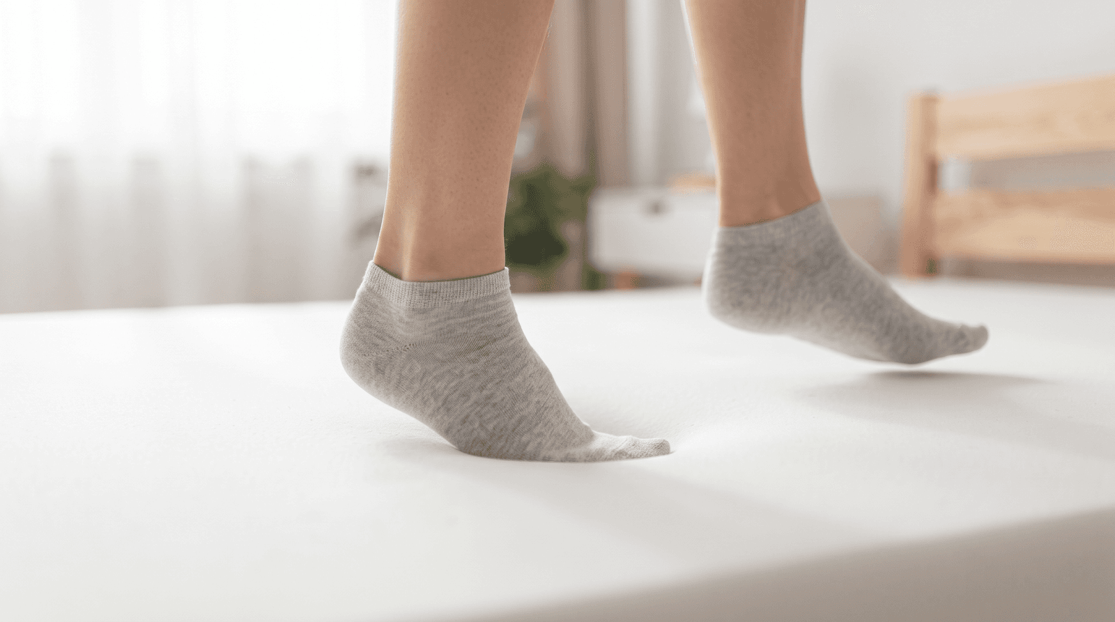 Feet in socks walking gently across the surface of a new mattress